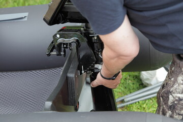 A men removes the small outboard motor from inflatable boat transom, the problem of outboard motors...