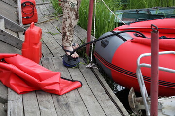 A man pumps up with air pump an inflatable boat on old wooden Pier before trip at summer day