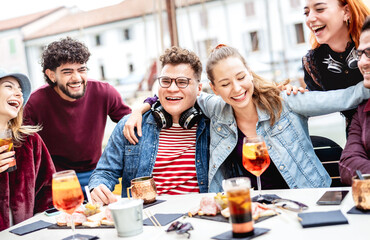 Trendy people on genuine fun moment at fancy pub restaurant - Life style concept with fashionable friends sharing happy hour time together at sidewalk cafe - Vivid filter with focus on central guy