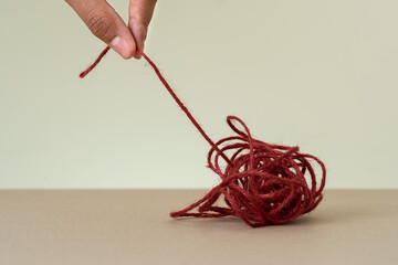 Close up photo of red loop and hand trying to untie. Concept of problem solving skills and...
