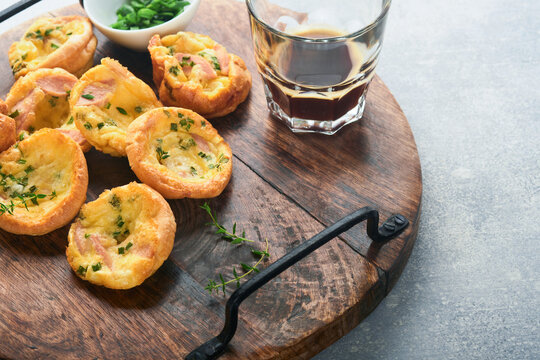 Delicious egg muffins with green onions, bacon, cheese and tomatoes on wooden board on light background. Healthy high protein and low carb breakfast. Homemade food.