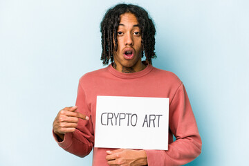 Young African american man holding crypto art placard isolated on blue background pointing to the side