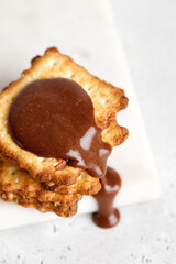 Crackers or cookies with chocolate paste pouring down. Food porn