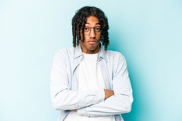 Young African American man isolated on blue background blows cheeks, has tired expression. Facial expression concept.