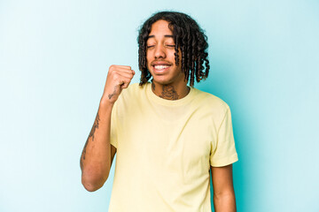 Young African American man isolated on blue background celebrating a victory, passion and enthusiasm, happy expression.