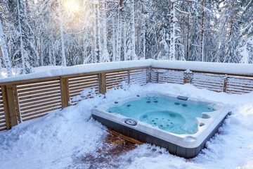 Modern outdoor hot tub in the middle of forest at sunset. The hot tub's soothing warm water relaxes...