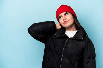 Young caucasian woman isolated on blue background touching back of head, thinking and making a choice.