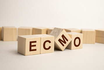 ecmo word written on wooden blocks and stethoscope on light blue background. insurance and medical concept