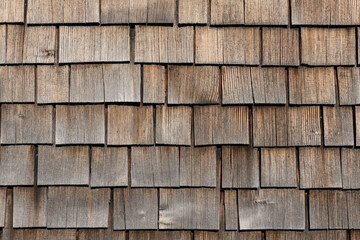 Verwitterte Holzschindeln an einer Hausfassade.

