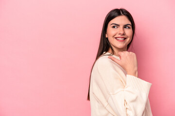 Young caucasian woman isolated on pink background points with thumb finger away, laughing and carefree.