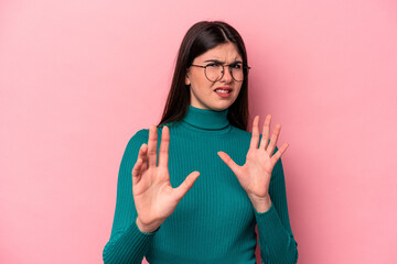 Young caucasian woman isolated on pink background rejecting someone showing a gesture of disgust.