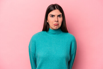 Fototapeta premium Young caucasian woman isolated on pink background shrugs shoulders and open eyes confused.