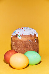 Close-up of colored Easter eggs and kulich on a yellow background. With a space to copy. High quality photo