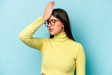 Young caucasian woman isolated on blue background forgetting something, slapping forehead with palm...