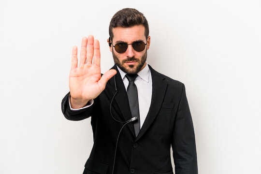 Young caucasian bodyguard man isolated on white background standing with outstretched hand showing stop sign, preventing you.