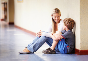 Bonding in the hallway. A teacher sitting with a student in the hallway talking.