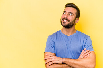 Young caucasian man isolated on yellow background smiling confident with crossed arms.