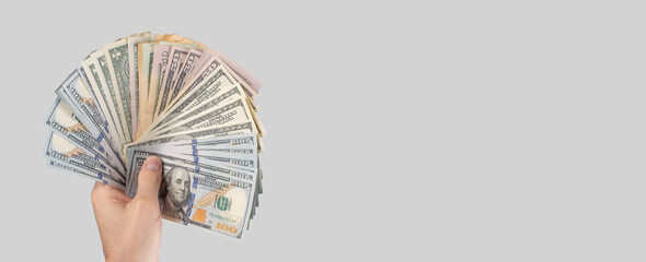 Banner with hand holding US one hundred dollar bills on grey background. American money. Place for text. High quality photo