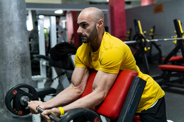 Obraz premium Young man lifting weights in the gym. Healthy lifestyle, training concept