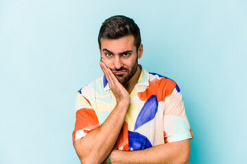 Young caucasian man isolated on blue background who is bored, fatigued and need a relax day.