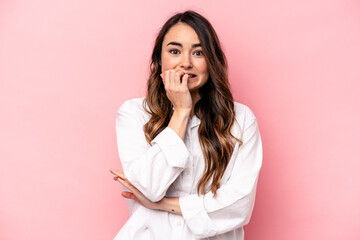 Young caucasian woman isolated on pink background biting fingernails, nervous and very anxious.