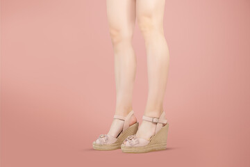 Studio shot of a young woman's legs in a pair of pink platform wedge shoes on pink background