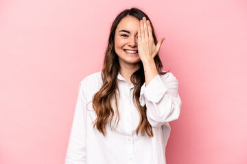 Young caucasian woman isolated on pink background having fun covering half of face with palm.