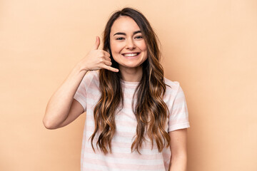 Young caucasian woman isolated on beige background showing a mobile phone call gesture with fingers.
