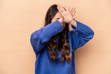 Young caucasian woman isolated on beige background keeping two arms crossed, denial concept.