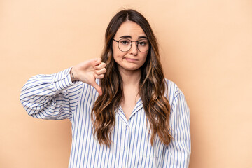 Young caucasian woman isolated on beige background showing thumb down, disappointment concept.