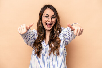 Young caucasian woman isolated on beige background raising both thumbs up, smiling and confident.