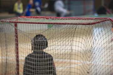 View of floorball match game, court hall indoor venue with junior teenage children school team playing in the background, floor ball hockey match game on arena stadium, copy space