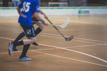 View of floorball match game, court hall indoor venue with junior teenage children school team playing in the background, floor ball hockey match game on arena stadium, copy space