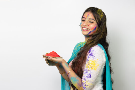 Young smart indian girl face coloured with gulal and plate full of color powder for festival of colours Holi, a popular hindu festival celebrated across india advertisement isolated white background