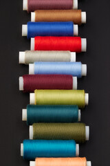 Multi-colored threads and sewing accessories on a black background.