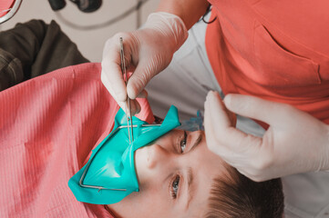 The dentist treats the child's tooth using a rubber dam.