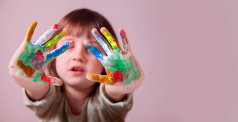 Portrait of beautiful young girl with colorful painted hands. Selective focus on hands.