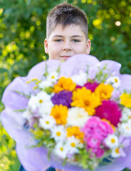 Teen boy with a bouquet of flowers in nature