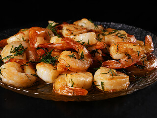 Fried king prawns on a glass plate, black background close-up