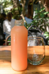 Botella de vidrio con jugo de pomelo junto a vaso de vidrio