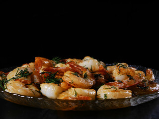 Fried king prawns on a glass plate, black background, space for text
