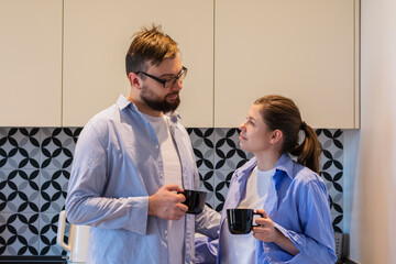 Young couple two friends man woman in casual clothes in the kitchen at home relaxing in the morning
