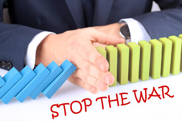 Businessman Stopping The Effect Of Domino With Hand At Desk