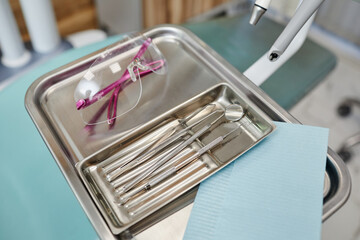 Background image of sterile metal tools on tray in modern dental clinic, copy space