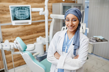 Waist up portrait of Muslim young woman as female dentist in modern dental clinic looking at camera, copy space