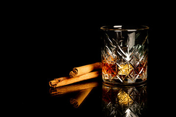 whiskey glass with metal ices, decorated with cinnamon sticks on a black background