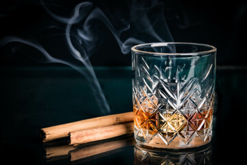 whiskey glass with metal ices, decorated with cinnamon sticks on a black background