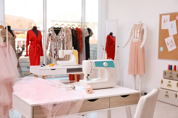 Obraz na płótnie Canvas Sewing machine, thread and fabric on table in dressmaking workshop