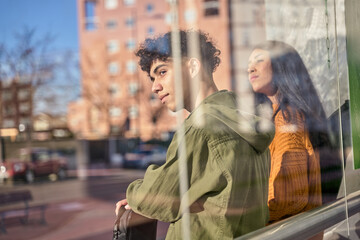 Fototapeta premium Two students while waiting for transport at the bus or tram stop to go to university. concept of sustainable transport.