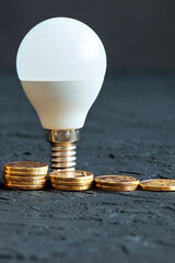 Energy saving. Energy saving light bulb. Money coins on a dark background. Energy saving. Stack of coins.Environmental protection